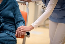 Close-up of doctor holding senior patient hand sitting in wheelchair